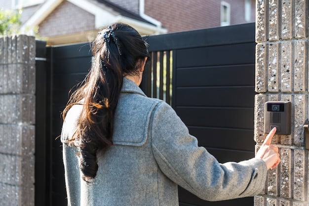A homeowner is inspecting the safety sensor of their garage door opener. The sensor is mounted near the ground on the sides of the door, and the person is checking the alignment and cleanliness of the sensor.
