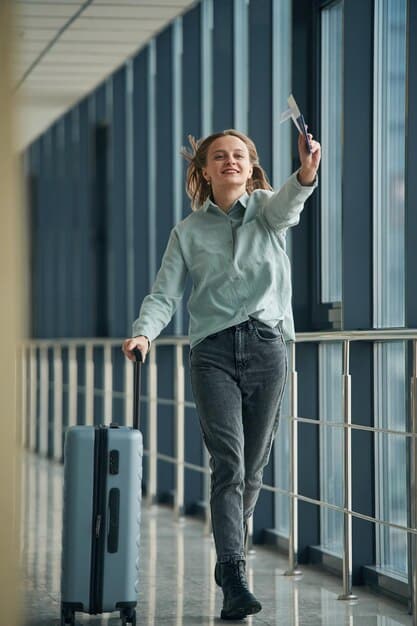 A traveler smiling and confidently walking through an airport terminal, pulling a suitcase with a tag indicating elite status in an airline loyalty program.