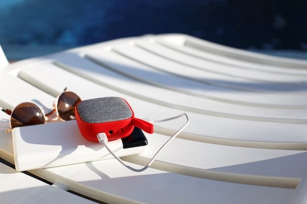 A close-up shot of a portable Bluetooth speaker undergoing a water resistance test. Water is being splashed onto the speaker, highlighting its rugged design and imperviousness to liquids. The background is a controlled lab environment.