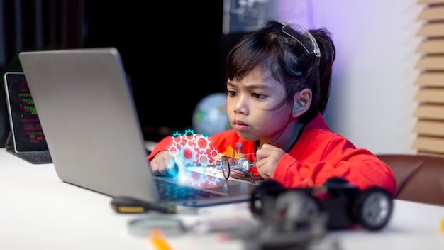 A young boy excitedly playing with a coding robot on a table, with a laptop displaying coding instructions in the background. The robot has blinking lights and interactive buttons.