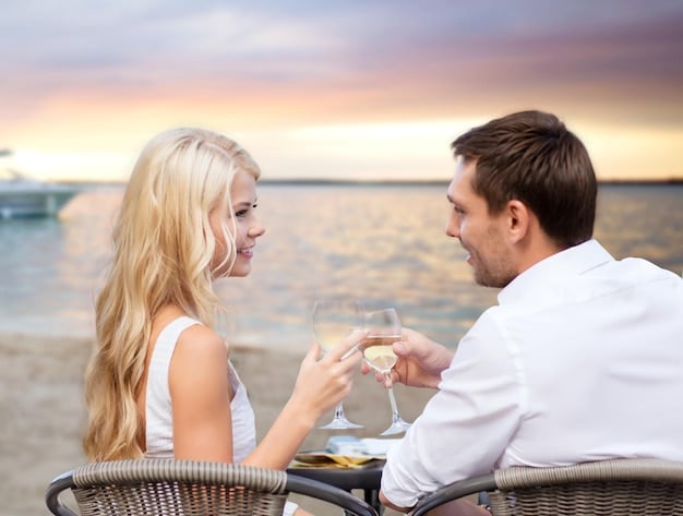 A serene image of a couple enjoying a private dinner on a white-sand beach at sunset. A personal butler is serving them champagne, highlighting the exclusivity and luxury of the experience.