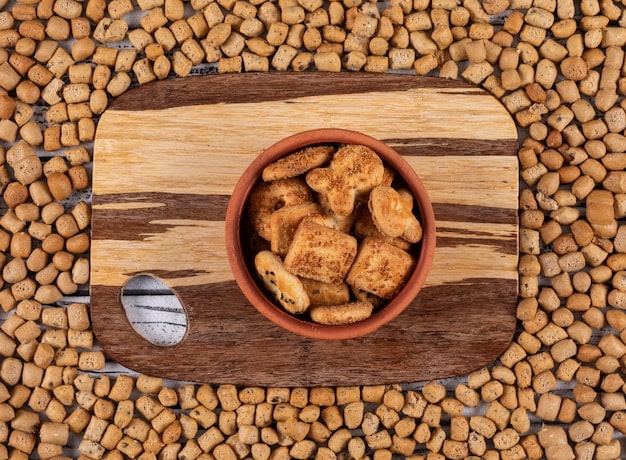 A close-up, mouth-watering shot of various gourmet pet treats arranged artfully on a wooden board. The treats include colorful dog biscuits, salmon-flavored cat snacks, and vegetable-based chews, highlighting the variety and quality of options available for pet lovers.