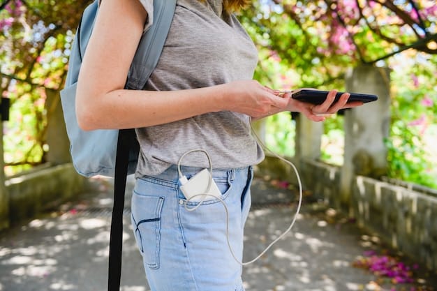 A close-up of a traveler using a portable charger to power their smartphone on a bustling city street. The charger is compact and easily fits into their pocket.