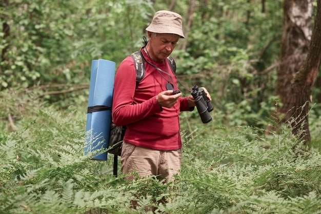 A traveler hiking through a lush forest, wearing a waterproof backpack and using a portable water filter to drink from a stream.