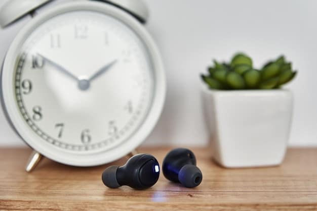 A pair of sleek, black noise-cancelling earbuds resting inside their opened charging case on a dark wooden desk, with a soft, out-of-focus background of a home office.