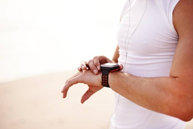 A close-up shot of a man's wrist wearing a sleek, modern smartwatch, displaying health metrics like heart rate or steps, in a minimalist setting.